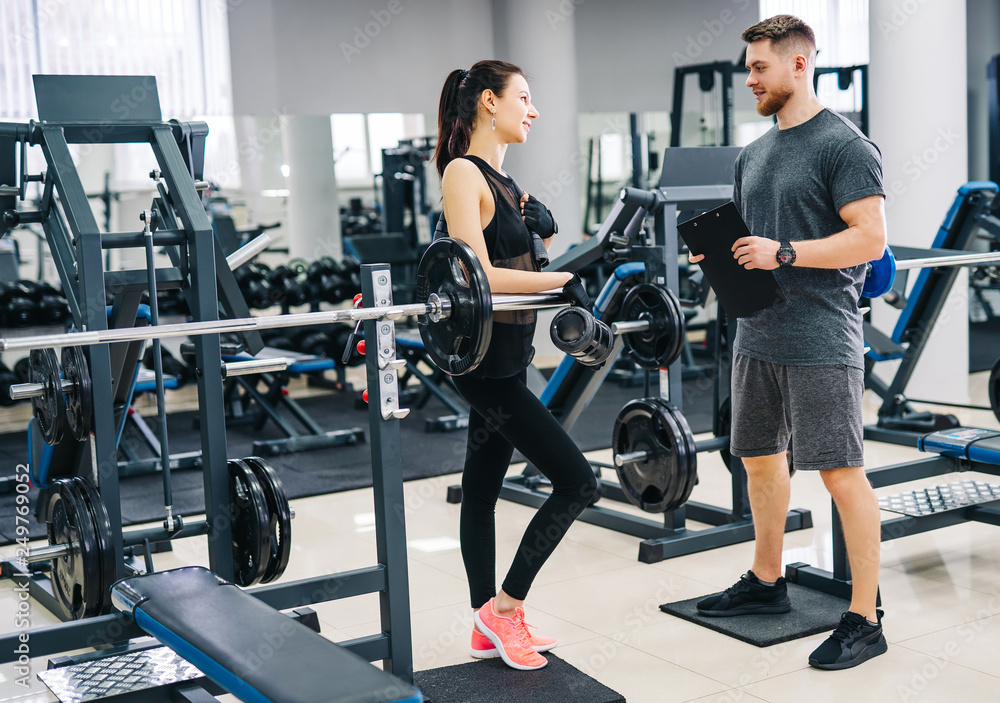 Personal trainer and client looking at his progress at the gym. Athletic man and woman wearing sportswear. Personal trainer and client looking at his progress at the gym. Athletic man and woman wearing sportswear.
