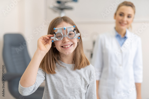 Fototapeta Naklejka Na Ścianę i Meble -  Cute little girl wearing optical trial frame while visiting ophthalmologist