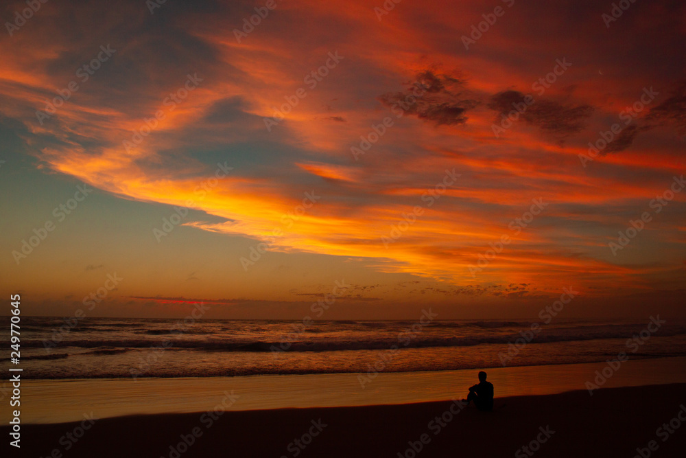 Young man sitting outdoors watching the sunset. Thinking and relaxing concept, Australia