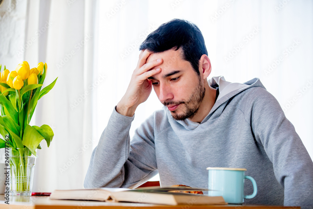 man sitting at table with cup of coffee or tea and book. man sitting at table with cup of coffee or tea and book.