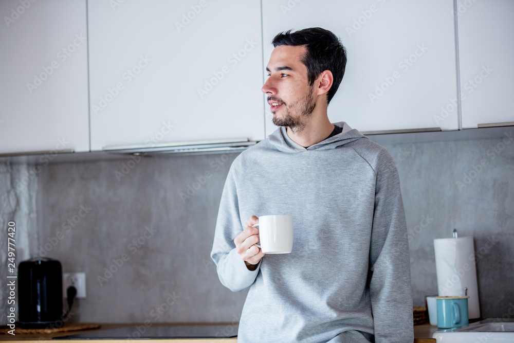 Young man with cup of coffee staying at kitchen at home Young man with cup of coffee staying at kitchen at home