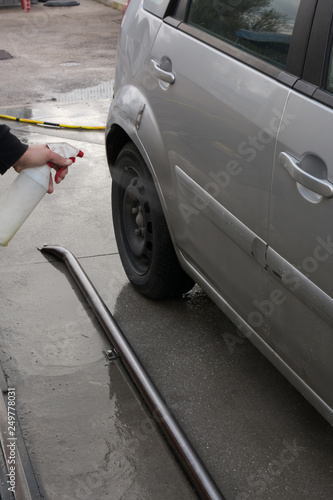 Man Spraying Car Soap for Washing a Car on Blurred Background