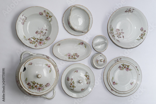 Set of vintage ceramic factorycrafted tableware with flowers of subtle colors on white background, 11 pieces, top view