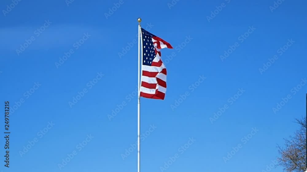 American flag on pole is waving in a clear blue sky. American flag on pole is waving in a clear blue sky.