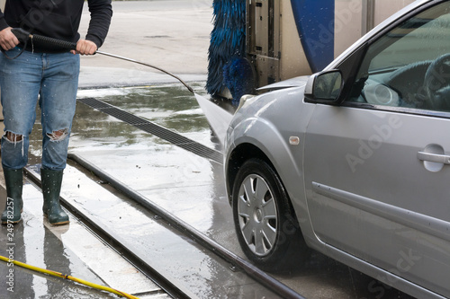 Man Using Water Pressure Machine to Wash a Car on Blurred Background © daniele russo