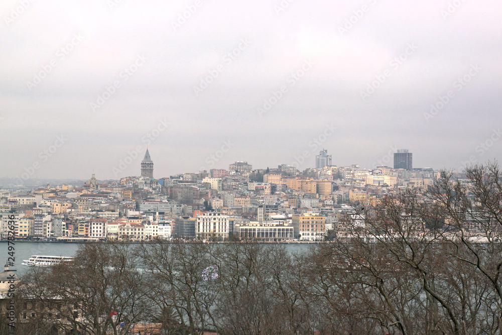 Obraz premium View of Istanbul through the Bosphorus and Golden Horn. Urban landscape with Galata Tower. Travel photography. Cloudy spring day.