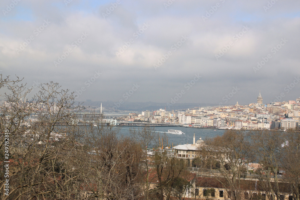 View of Istanbul through the Bosphorus and Golden Horn. Urban landscape with Galata Tower. Travel photography. Cloudy spring day.
