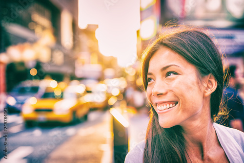 Fotografia, Obraz Happy people New York city lifestyle young Asian woman smiling in sunset walking in street with taxi cabs traffic sun shining down in downtown Manhattan, New York City