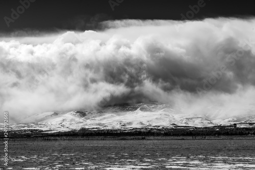 Dramatic clouds and snowstorm over a snowcapped mountain.