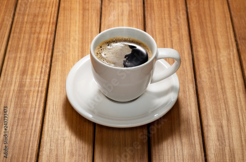 Close up photo of a coffee cup and saucer over a wood table