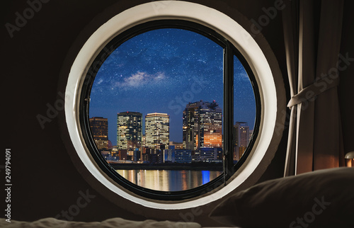 Round window frame in bedroom at night with city view