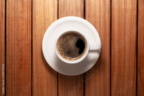 Top view photo of a coffee cup and saucer over a wood table background