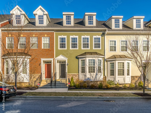 Typical American town house, town home neighborhood with colorful real estate houses at a new construction East Coast Maryland location with blue sky