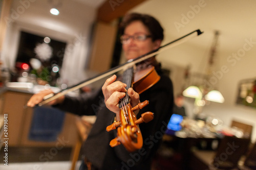 A woman plays a violin in a room