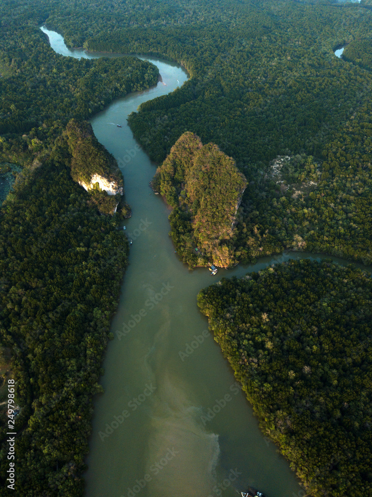 Image from drone of river in Krabi town, Thailand. Green trees, mountains and rocks around river.