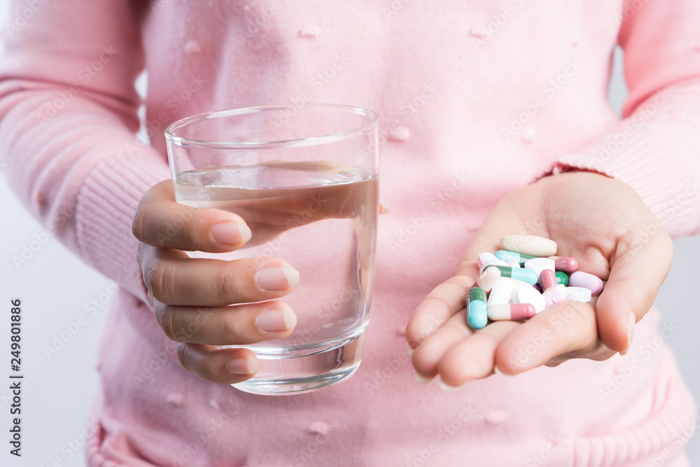 medicine, health care and people concept - close up of woman taking in pill and another hand holding a glass of clean mineral water. medicine, health care and people concept - close up of woman taking in pill and another hand holding a glass of clean mineral water.