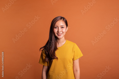 Young Asian woman portrait over orange background, smile happy studio shot