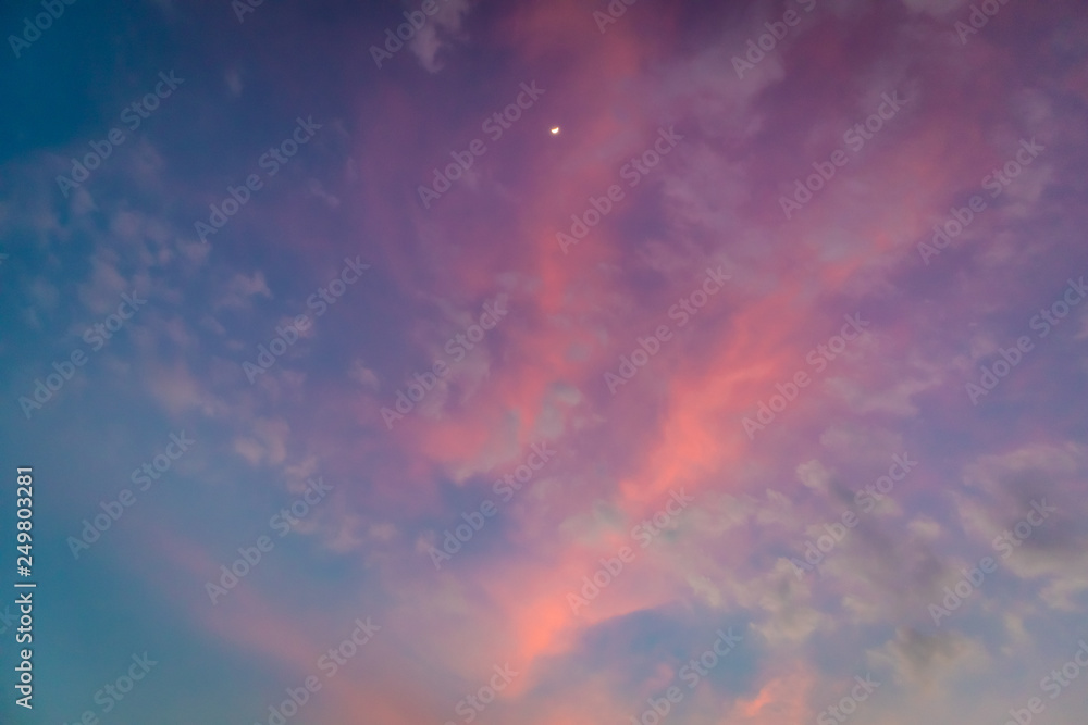 White moon on colorful vivid pink and blue twilight sky.