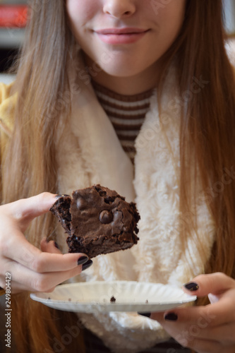 Young woman holding brownie, slight smile