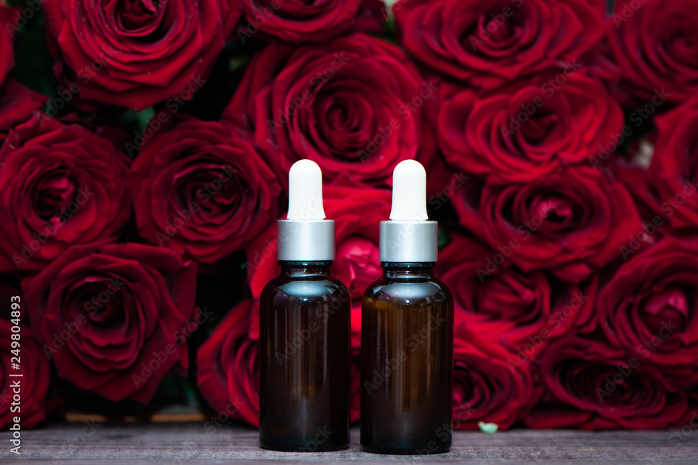 Rose oil, Bottles and fresh flower and leaves on a natural background, bio, organic , nature cosmetics concept Rose oil, Bottles and fresh flower and leaves on a natural background, bio, organic , nature cosmetics concept