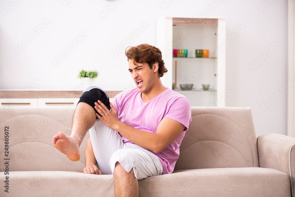 Young man with injured knee recovering at home Young man with injured knee recovering at home