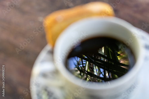 reflection of a palm tree in the coffee liquid with toast in the blurred background © Fabio