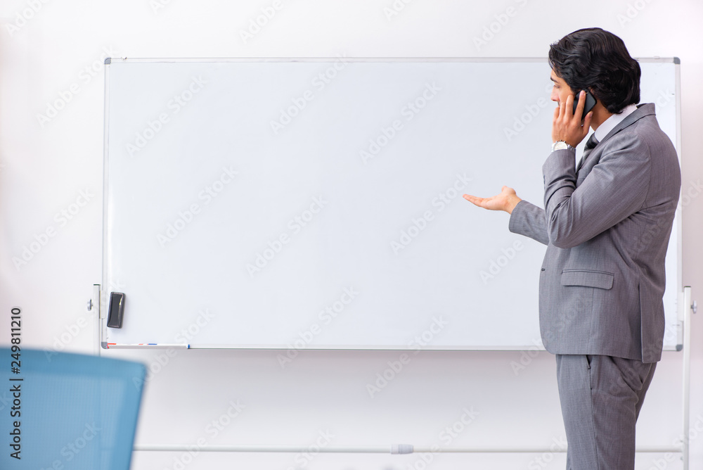 Young handsome businessman standing in front of whiteboard Young handsome businessman standing in front of whiteboard
