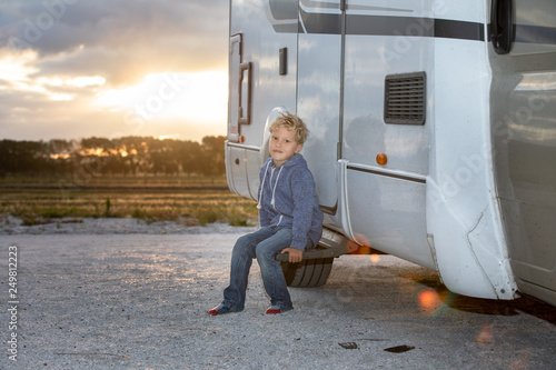 Young boy sitting outside his motor home at sunset