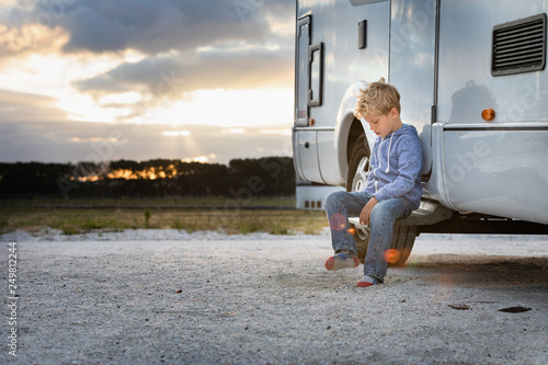 Young boy sitting outside his motor home at sunset