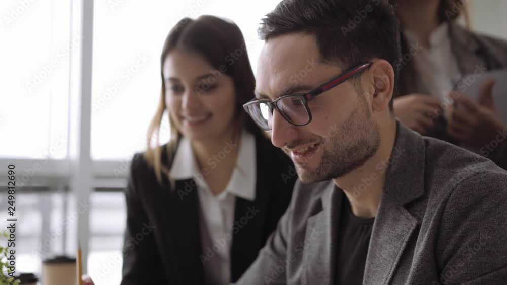Close up of candid creative businessman working in office and discussing start up ideas and projects with team Close up of candid creative businessman working in office and discussing start up ideas and projects with team