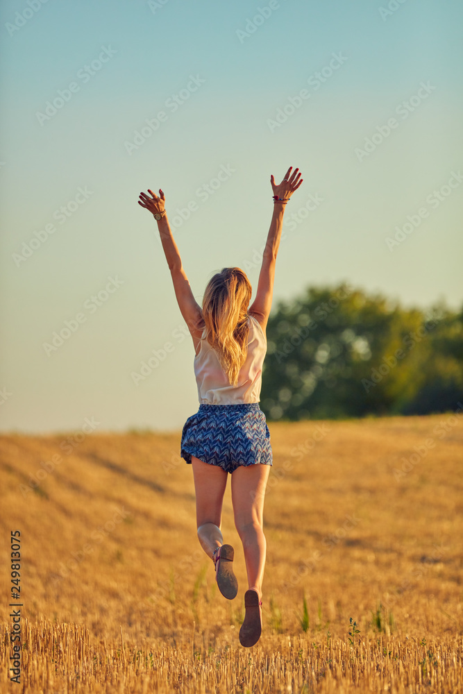 Cute young woman jumping in a wheat field. Cute young woman jumping in a wheat field.
