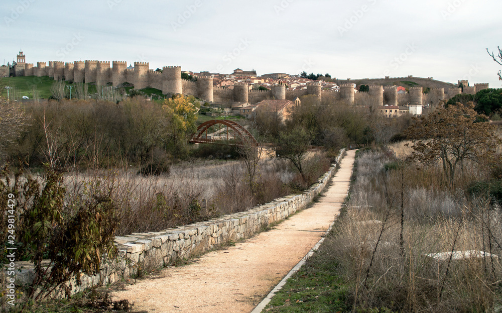 The medieval city of Ávila, surrounded by a fortress wall and the road leading to it.