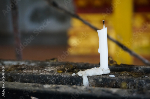 Melted white candle on grunge table in Buddhist temple