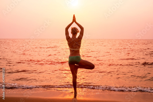 Beautiful young woman practic yoga at the beach. Early morning exercise © romaset