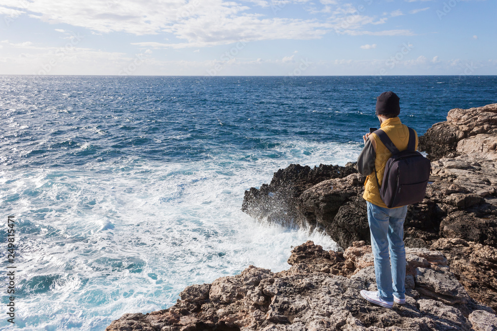 man tourist in yellow vest with backpack on rock cliff in Malta man tourist in yellow vest with backpack on rock cliff in Malta