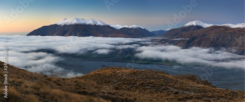 The valley is flooded in mist in a mountain environment. Over the fogs, only the high peaks of the mountains rise beneath the sunny sky. Misty morning on the Southern Island New Zealand, Christchurch  © Michal
