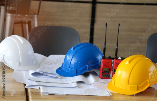 yellow, blue and white hard safety helmet for safety project of workman as engineer on table wooden.