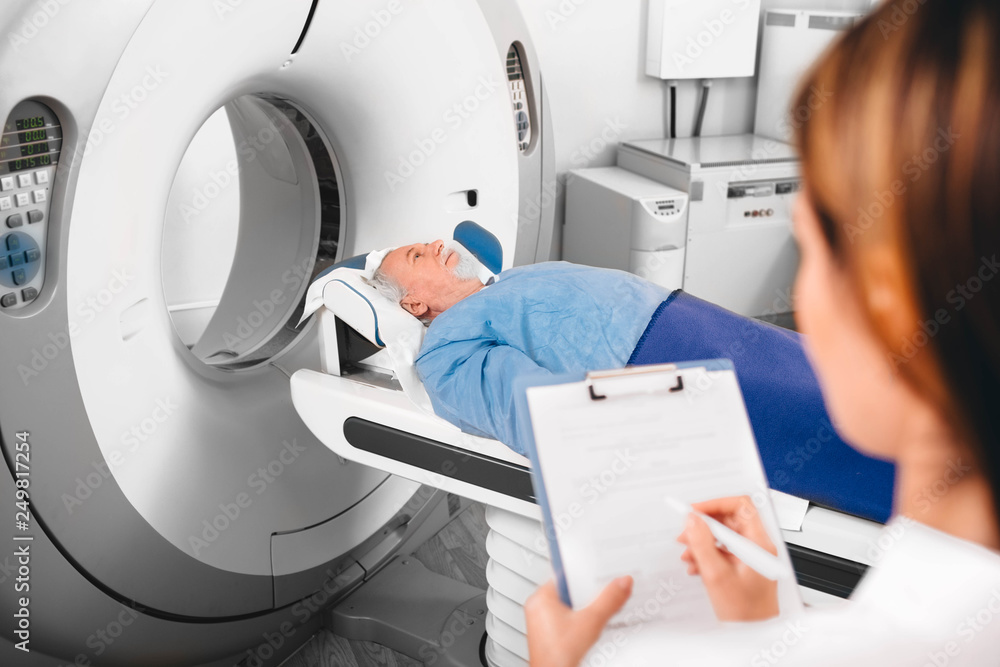 doctor write into medical chart after CT Scan in hospital.CT Scan senior patient doctor write into medical chart after CT Scan in hospital.CT Scan senior patient
