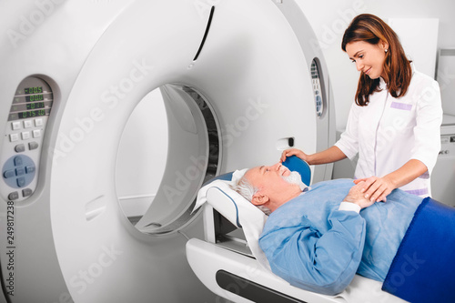 Photos Radiographer reassuring senior man going into CT scanner in hospital