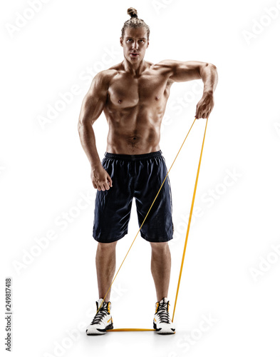 Man with athletic body performs exercises using a resistance band. Photo of muscular man isolated on white background. Strength and motivation. Full length