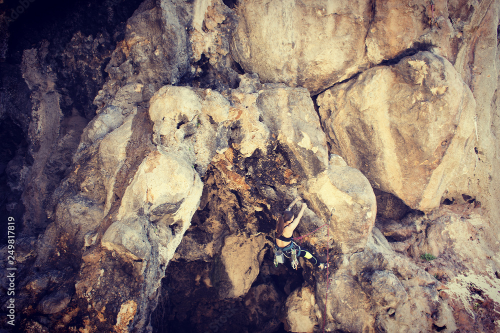 Obraz premium Girl rock climber climbs difficult route on the cliffs.