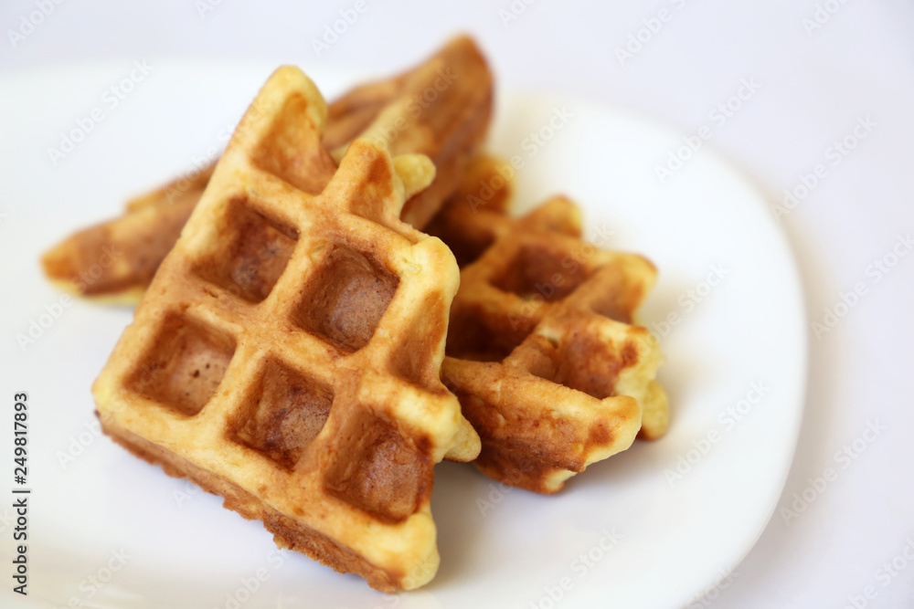 Belgian waffles in white plate. Healthy breakfast close up, pieces of freshly baked classic wafer Belgian waffles in white plate. Healthy breakfast close up, pieces of freshly baked classic wafer