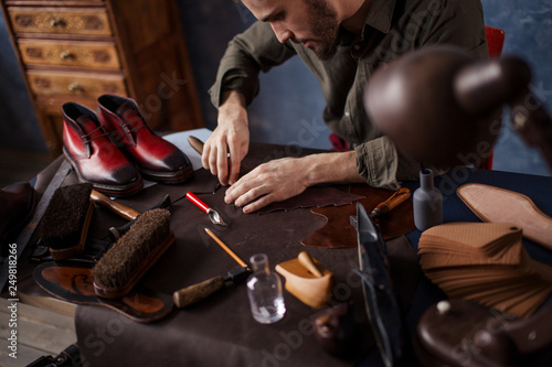 uung talented craftsman making a leather item in the blue room . close up cropped photo