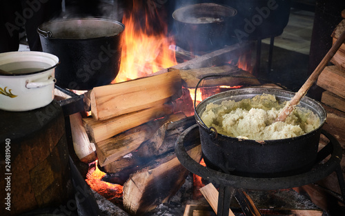 Traditional georgian food, hominy (mamaliga) is cooked in the large cooking pot on fire photo