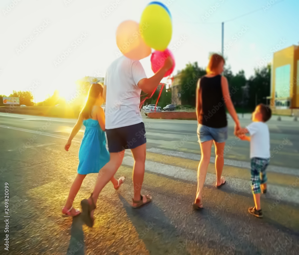 Fototapeta premium Abstract, blur background, defocusing - image for the background. Happy family playing with balloons on the road in the sunset time.