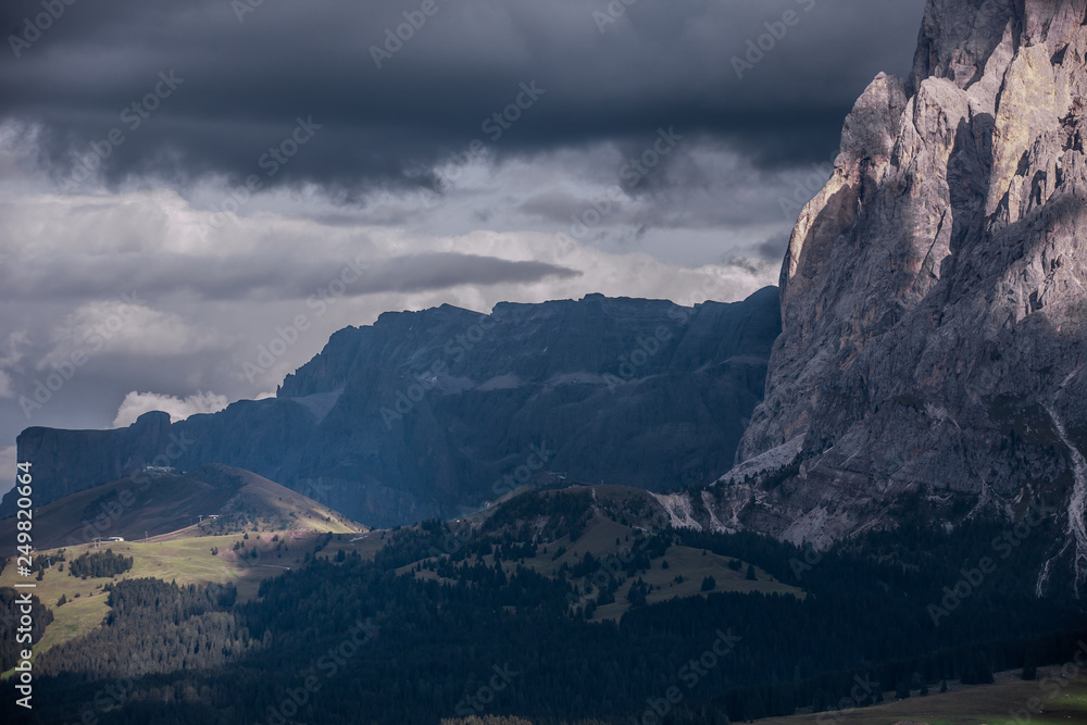 Massive mountains with clouds in the evening sun. A lot of stone structure and partly covered with clouds. Tele Objective. Langkofel Seiser Alm