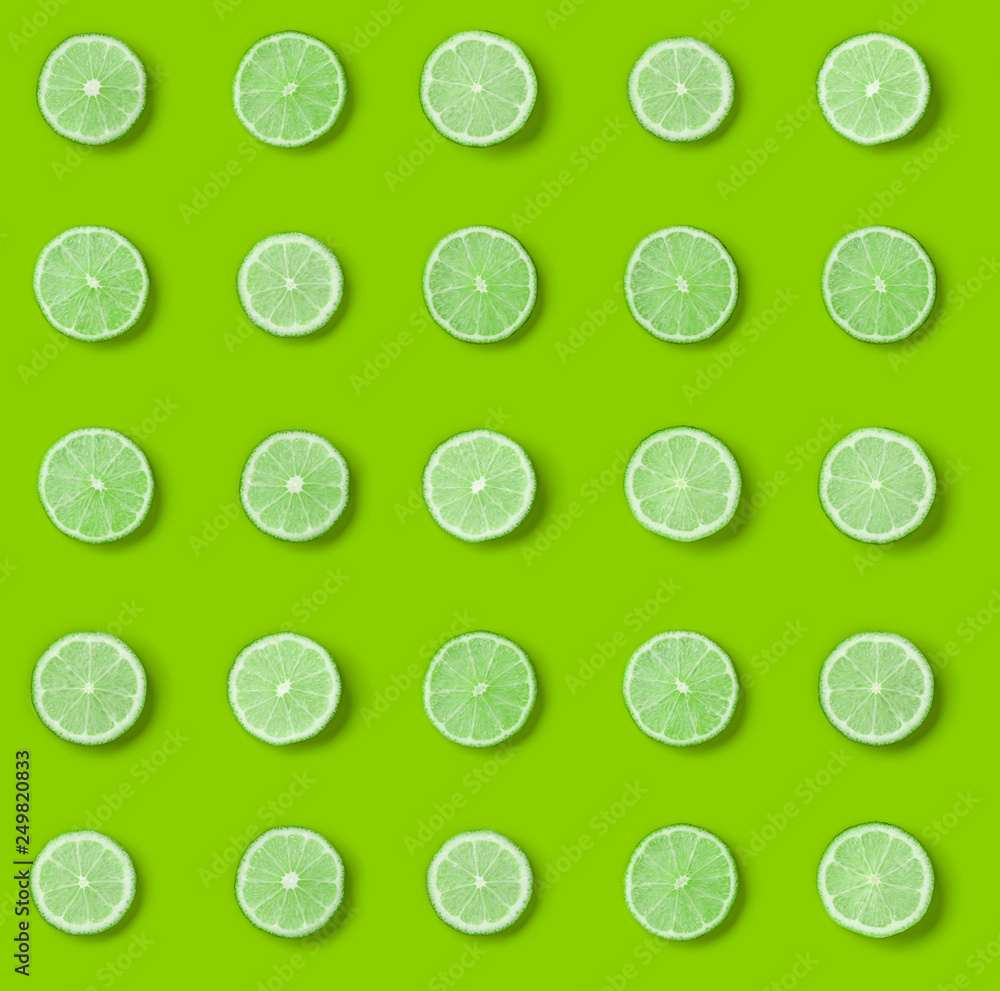 Fruit pattern of lime slices on green background. Flat lay, top view. .  Pop art design, creative summer concept.