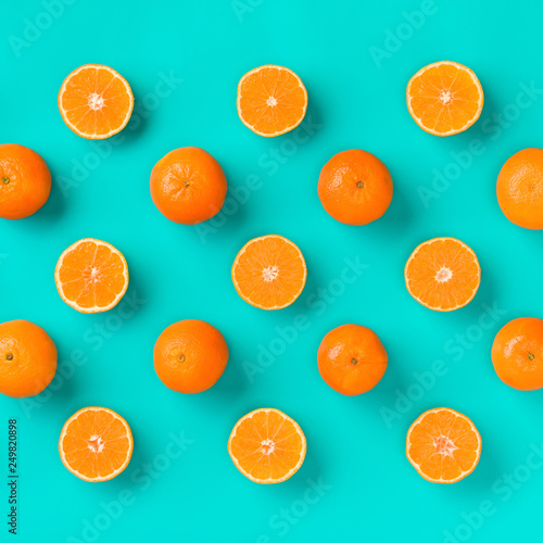 Fruit pattern of fresh mandarin slices on blue background. Flat lay, top view. Pop art design, creative summer concept. Half of citrus in minimal style. Tangerine.