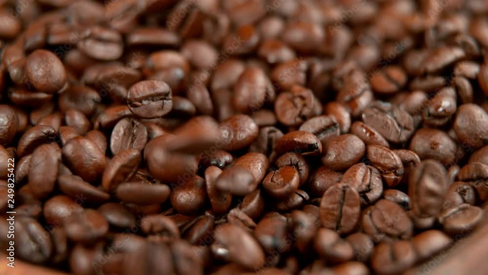 Roasted coffee beans rolling in wooden bowl in super slowmotion. Roasted coffee beans rolling in wooden bowl in super slowmotion.