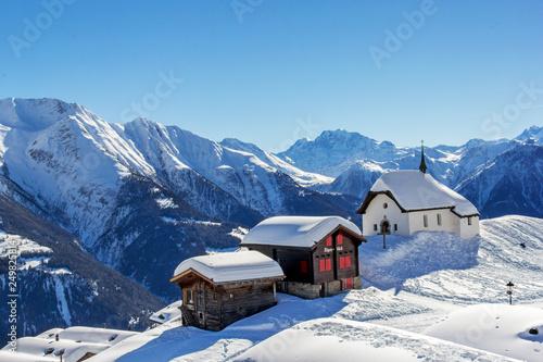 Chapel Maria in Snow (Kapelle zum Schnee) with two old chalets - the landmark architecture in the Swiss alps village Bettmeralp © Yü Lan
